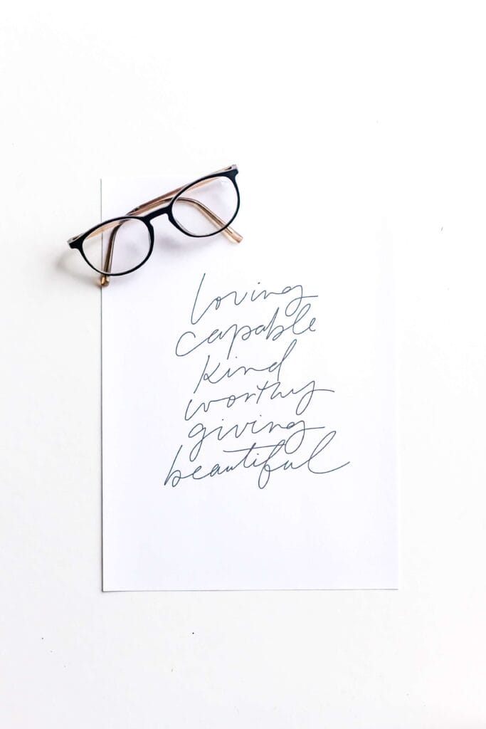 positive affirmations written down on paper, pair of glasses on the page