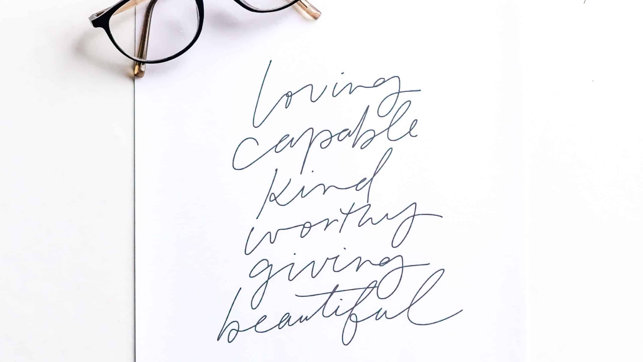 positive affirmations written down on paper, pair of glasses on the page